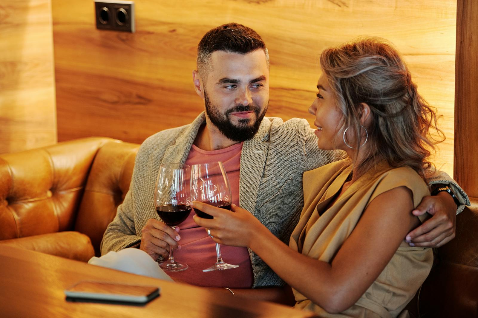 Couple Sitting Together in a Restaurant Holding Wine Glasses